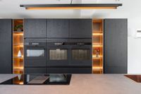 The new kitchen island and oven worktop with black front and state-of-the-art appliances