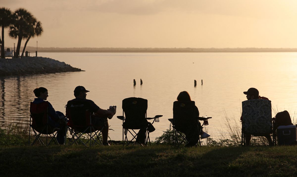 Space enthusiasts watch the sunrise from a park in Titusville, Florida several hours before NASA's Artemis II Space Launch System (SLS) rocket is scheduled to launch from the Kennedy Space Center on April 1, 2026.