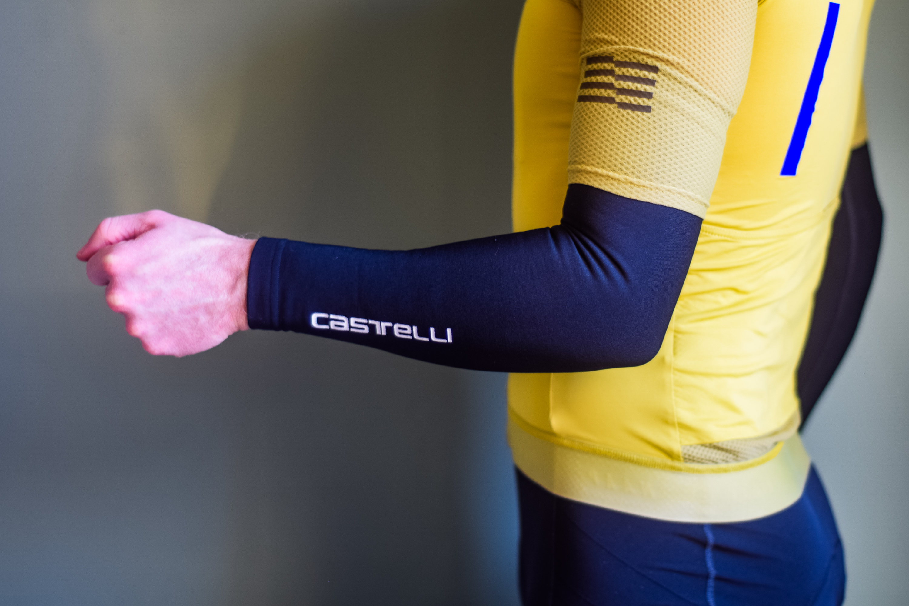 A man in a yellow cycling jersey wearing black arm warmers