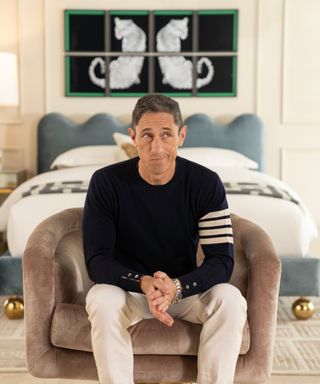 Jonathan Adler sitting in an armchair in front of a bed