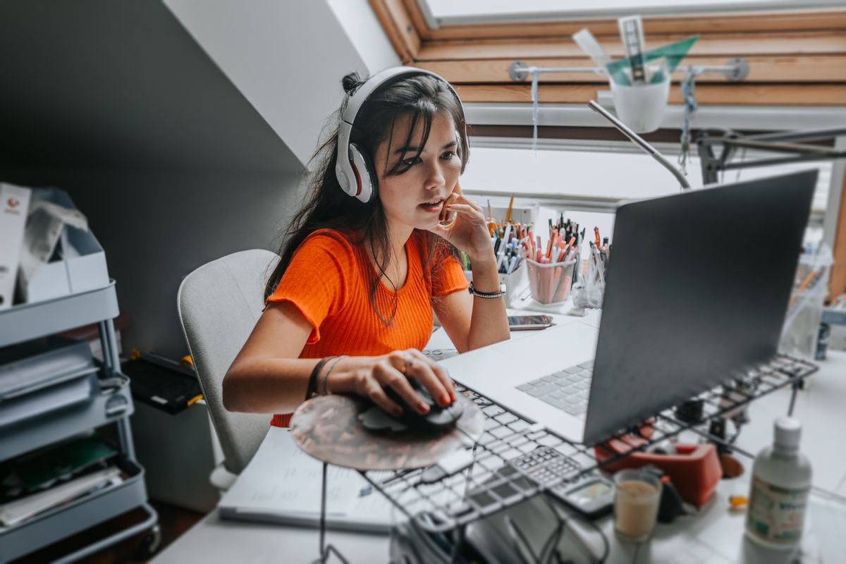 A woman working from home on a desk surrounded by hardware and office supplies