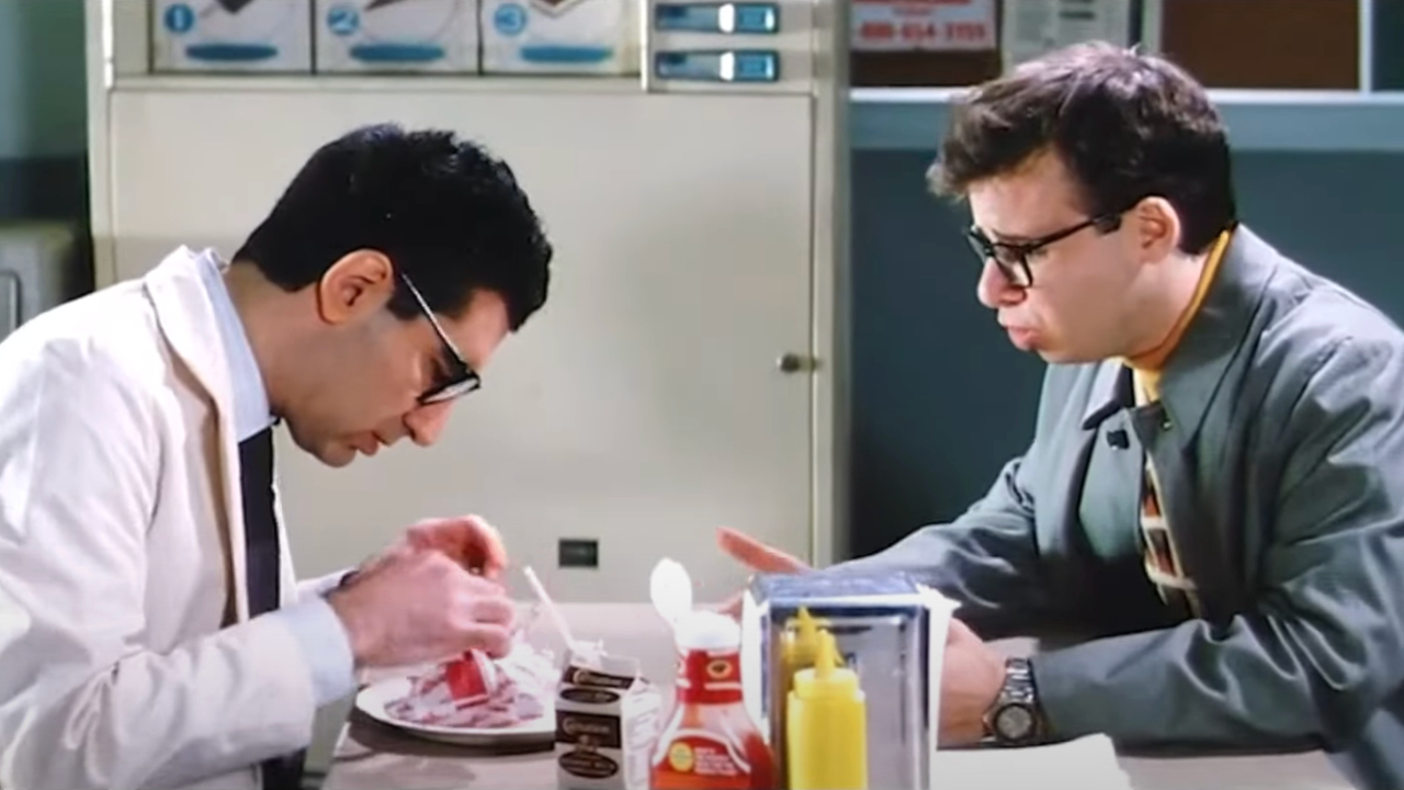Rick Moranis pleads with Eugene Levy while he tries to eat his lunch in Ghostbusters II.