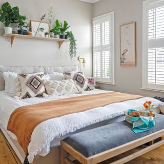 king size bed with blankets and cushions underneath shelf with plants