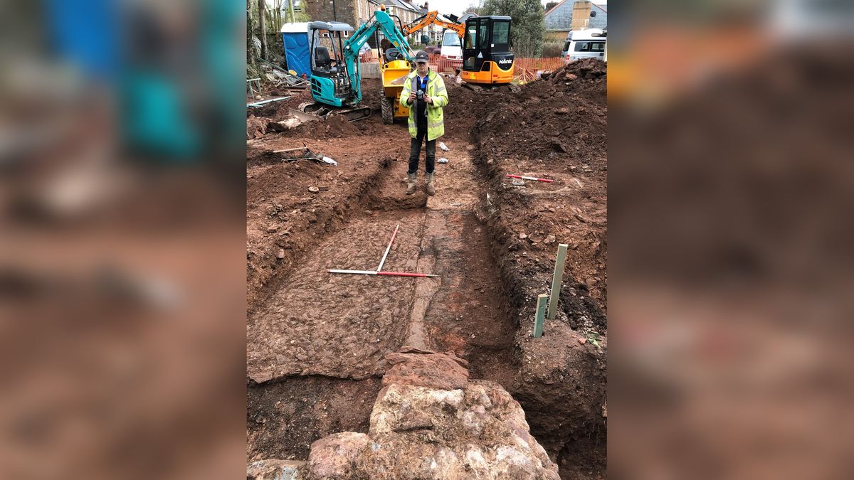 Archaeologist James Brigers takes a photo at the site of the bishop&#039;s palace. The remains of a medieval fireplace can be seen at the pointed end of the ranging pole and an ancient wall can be seen on the right of the photo. The finds also included a cobbled floor that was a later addition to the palace. 