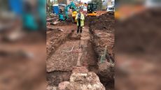 Archaeologist James Brigers takes a photo at the site of the bishop's palace. The remains of a medieval fireplace can be seen at the pointed end of the ranging pole and an ancient wall can be seen on the right of the photo. The finds also included a cobbled floor that was a later addition to the palace. 
