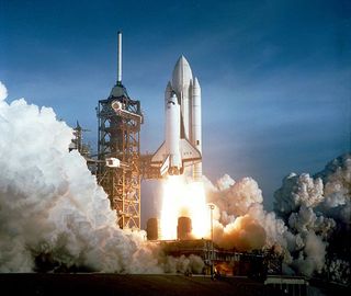 A rocket lifts off in a dramatic image, with billowing clouds of water vapor below.