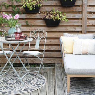 Decking area with metal garden furniture and rug on top of it