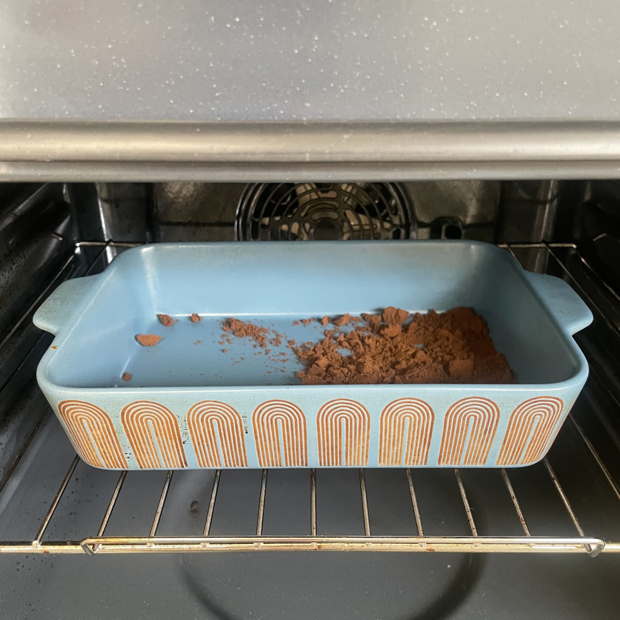 Coffee grounds in a blue dish inside of an oven