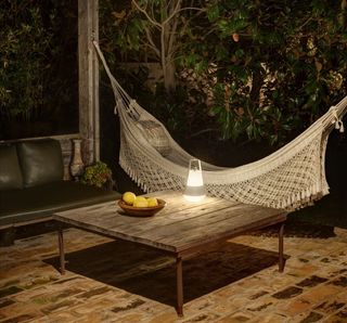 Brick patio with hammock and outdoor lamp on table