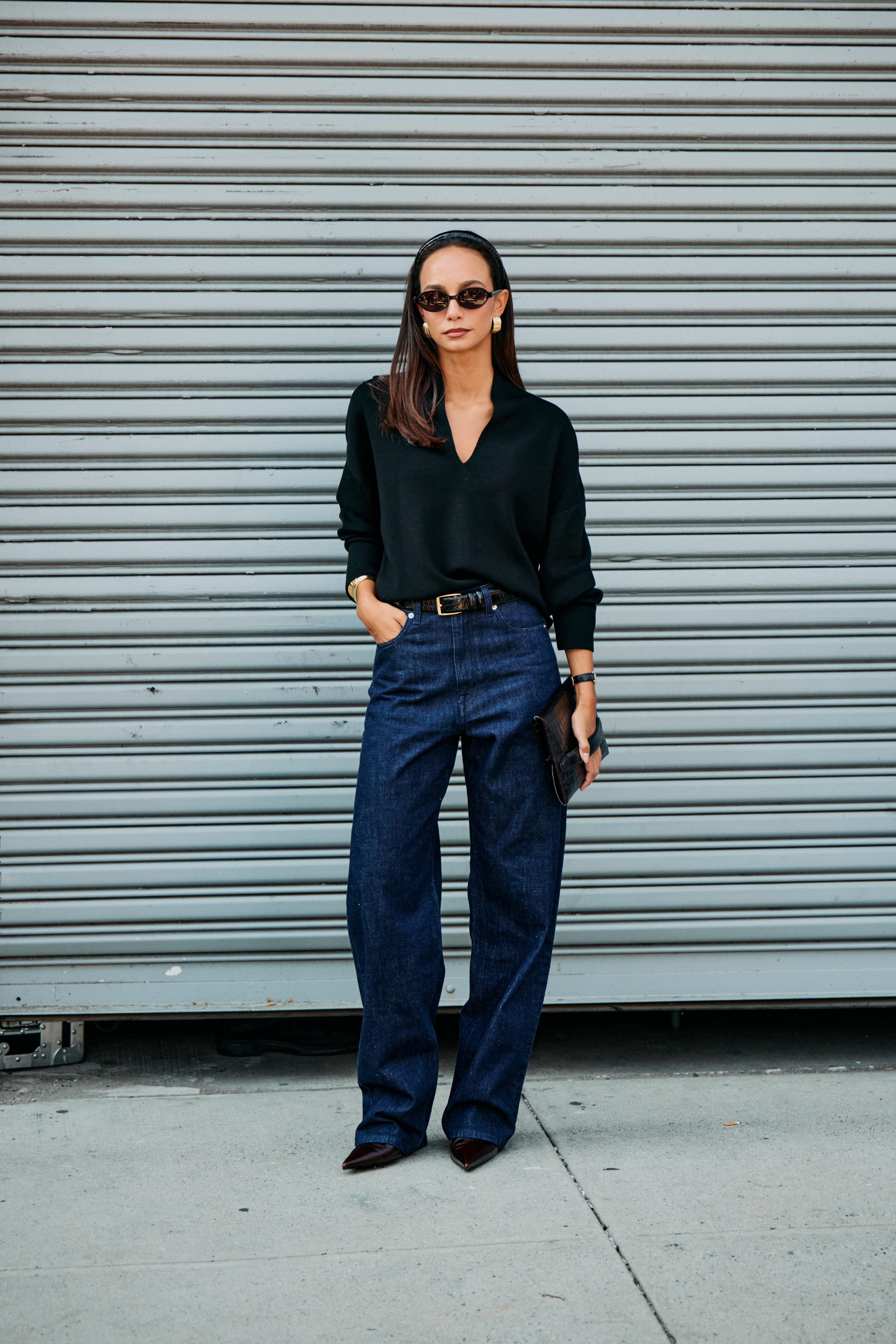 Woman in black blouse and dark rinse jeans.