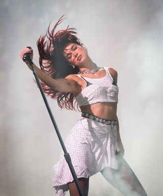 Dua Lipa onstage at Glastonbury wearing a studded t shirt as a skirt