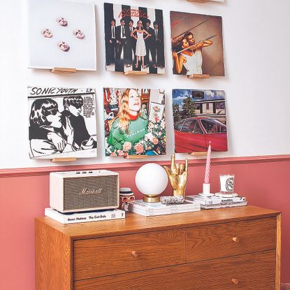 Living room with mid century sideboard and half-height pink painted wall.