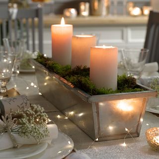 Christmas table setting with candles in tray as centerpiece and fairy lights