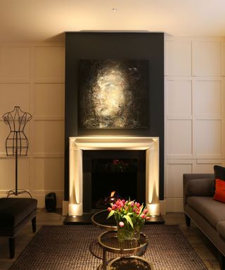 Small living room lighting ideas example with uplighting of a black and white painting above a fireplace.