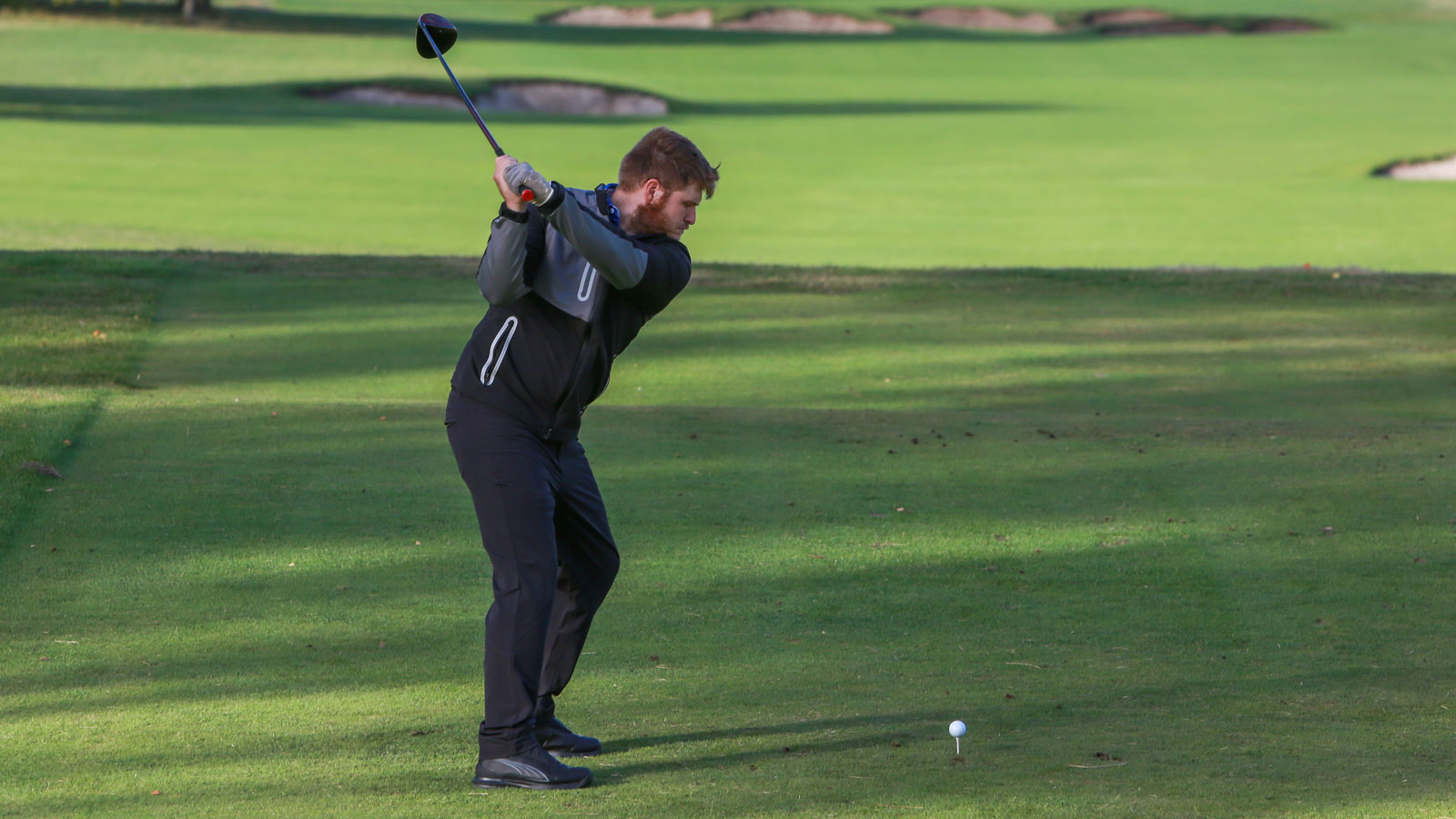 A golfer strikes a tee shot wearing the Puma DRYLBL Rain Waterproof Golf Pants