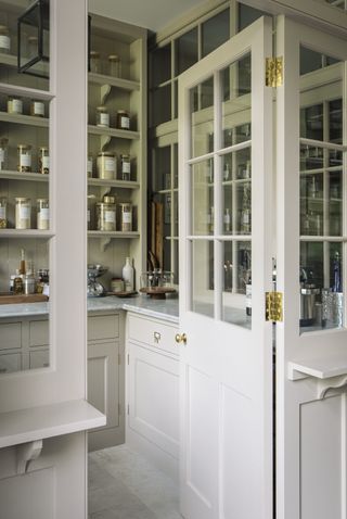 A view through the door of a white pantry with organized food jars on the shelves