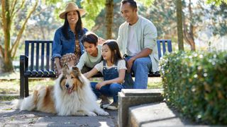 Family sitting on a bench outside with their dog