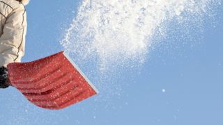 Throwing snow with a snowshovel against blue sky