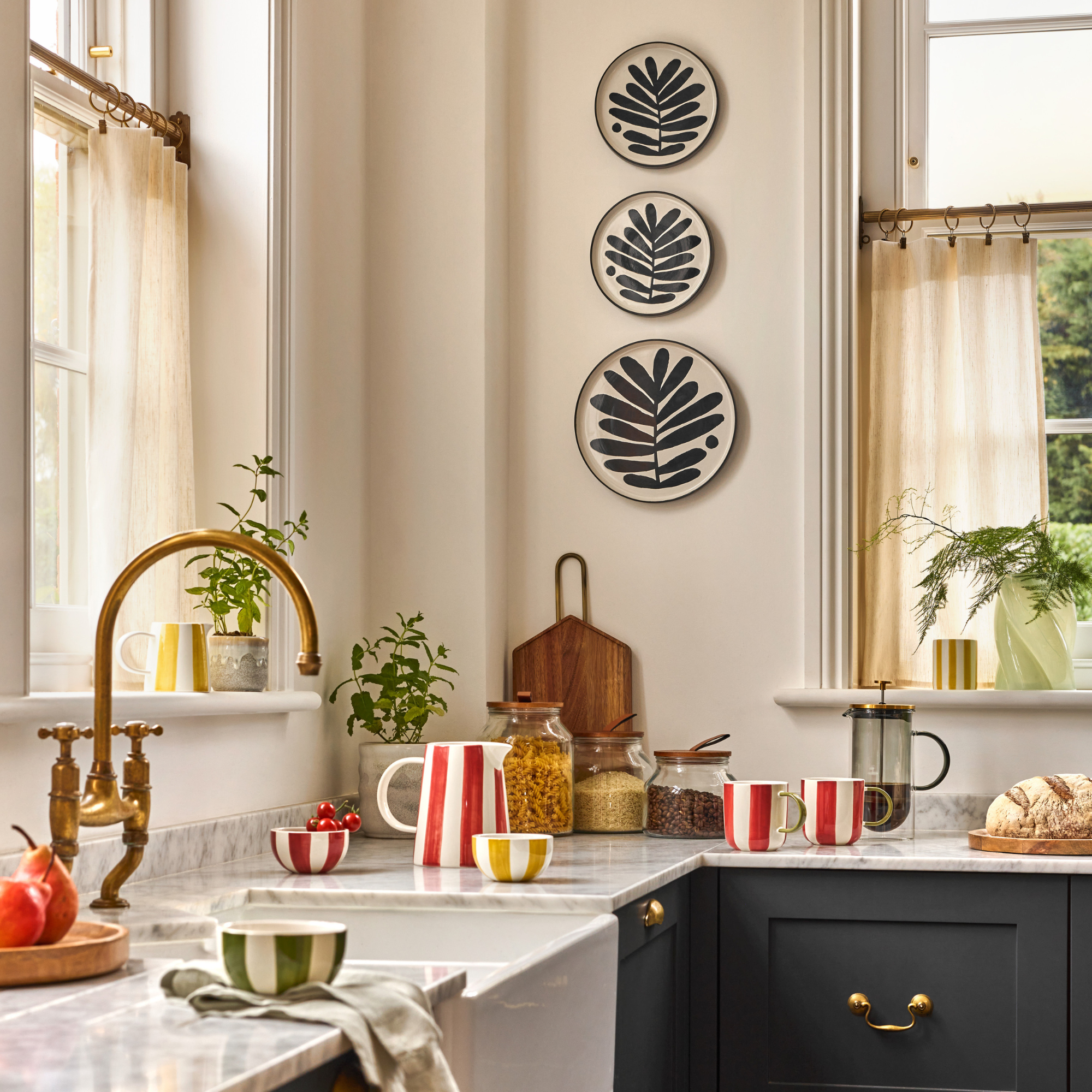 striped red mugs, jug and bowl. Green mug and yello bowl on kitchen counter.