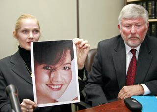 A woman holding up a portriat of Carita Ridgeway at a press conference