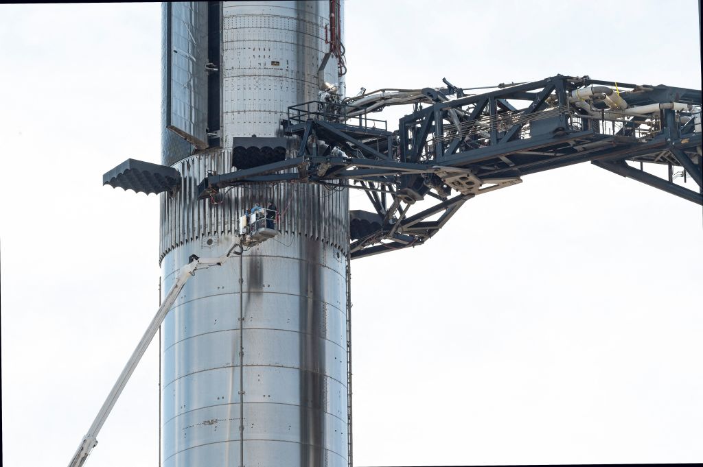 A team inspects SpaceX's first orbital Starship SN20 stacked atop its massive Super Heavy Booster 4 at the company's Starbase facility near Boca Chica Village in South Texas on Feb. 10, 2022.