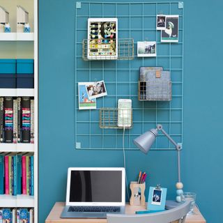 home office with blue wall desk laptop and wall storage