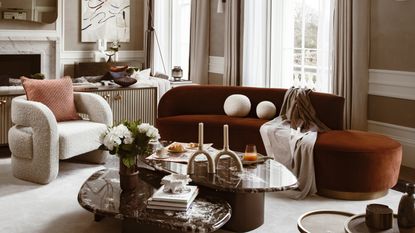 neutral living room with curved chestnut sofa, white curved chair, statement pendant and arched win