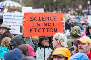 A man holds up a sign at the Science March on the Boston Common on April 22, 2017 in Boston, Massachusetts. The event is being described as a call to support and safeguard the scientific community