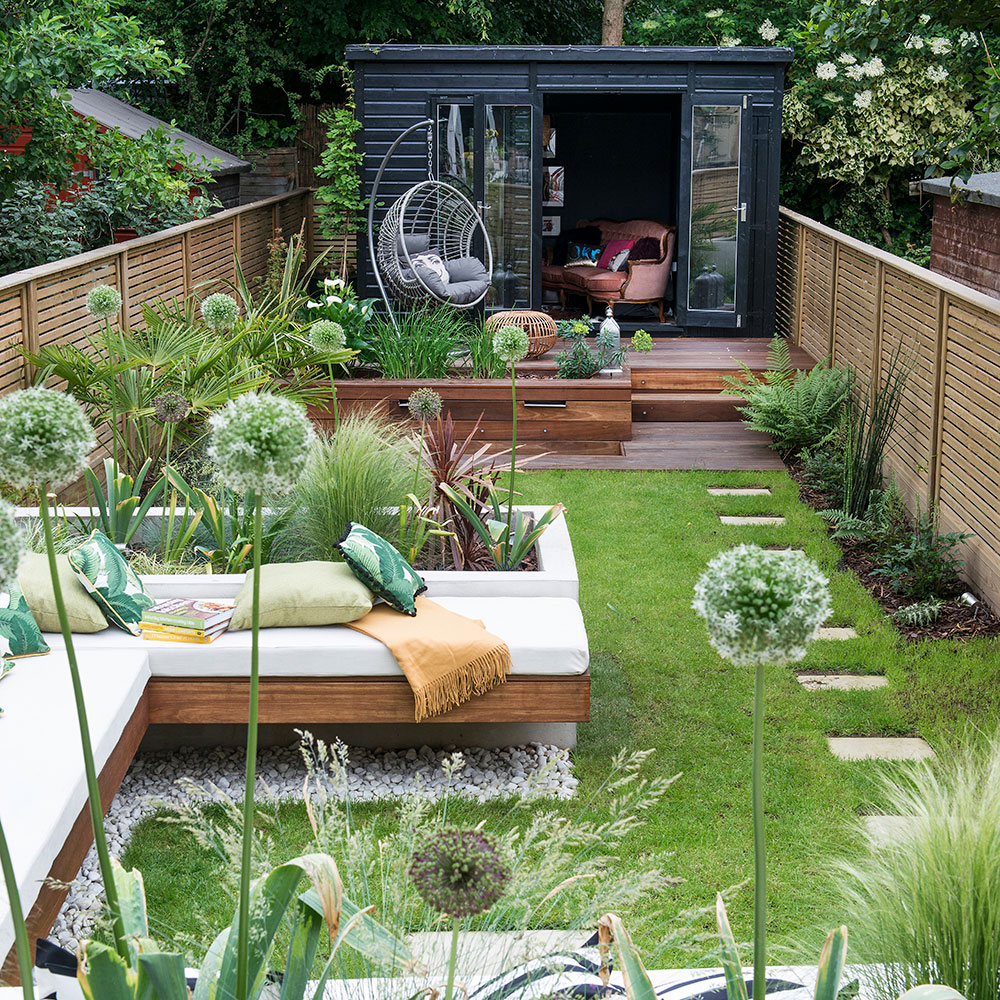 garden with corner sofa, stepping stones path on lawn and decking in front of garden room