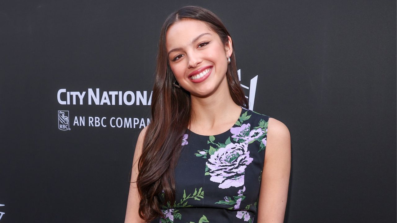 Olivia Rodrigo in foral dress against black background