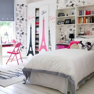 White bedroom with wallpaper, wooden floors, in built storage and desk