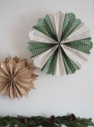 Christmas paper bag decorations, two hanging above mantel, green foliage