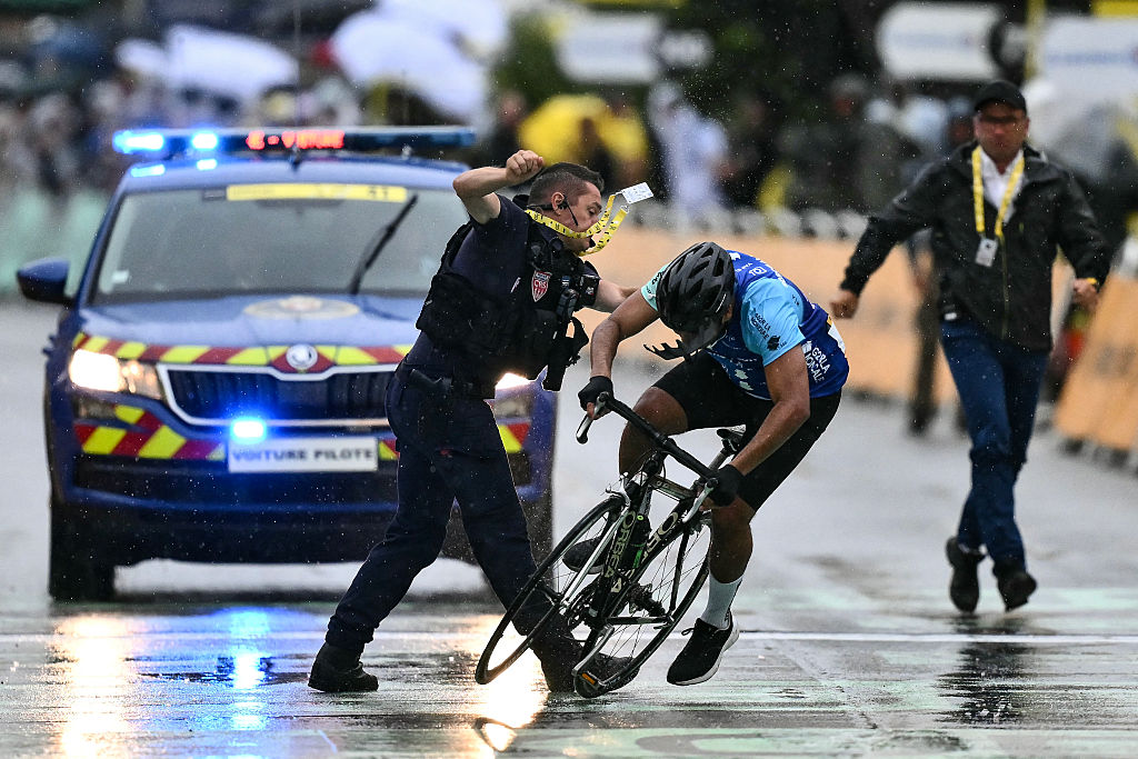 A French Republican Security Corps (CRS - Compagnies Republicaines de Securite) officer tackles an individual attempting to cycle across the finish line minutes before the final sprint of the 112th edition of the Tour de France cycling race, 160.4 km between Bollene and Valence, southern France, on July 23, 2025. (Photo by Marco BERTORELLO / AFP)