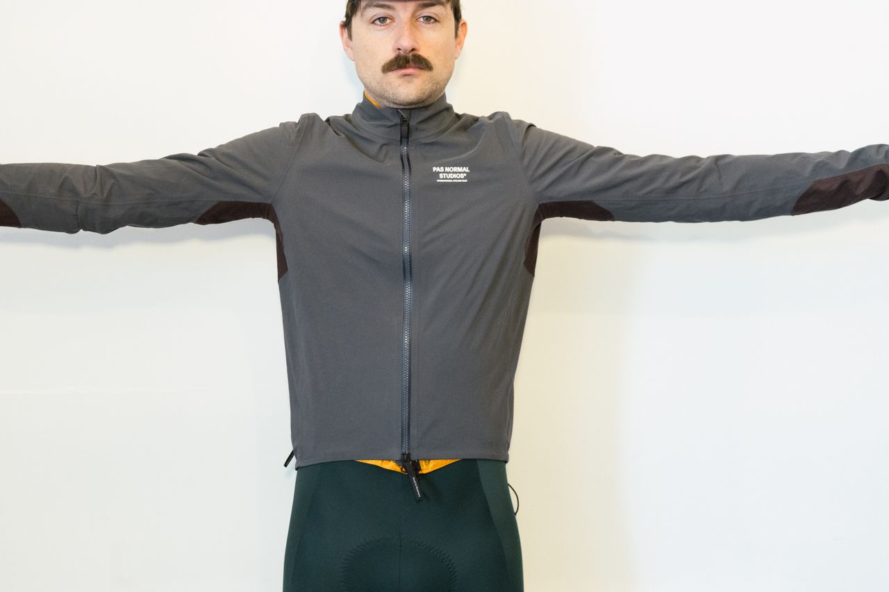 A white man in a grey jacket simulates different riding positions