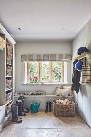 boot room with built-in storage, baskets and blind at window