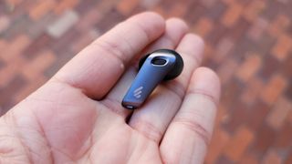 An Edifier NeoBuds Pro earbud in the palm of a hand, showing how small it is