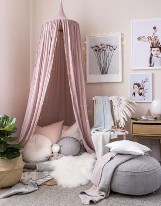 Pink kid's bedroom with a pink canopy and gallery wall