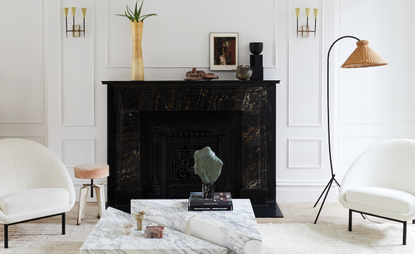 A living room with white walls, chairs and a black fireplace