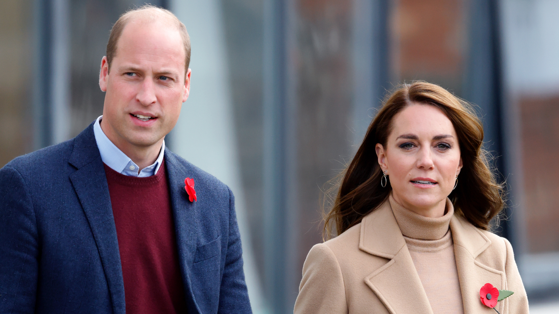 Prince William wears a red sweater and a navy coat and Princess Kate wears a beige coat with a matching turtleneck sweater