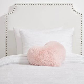 A white headboard with white bedding and a pink pillow