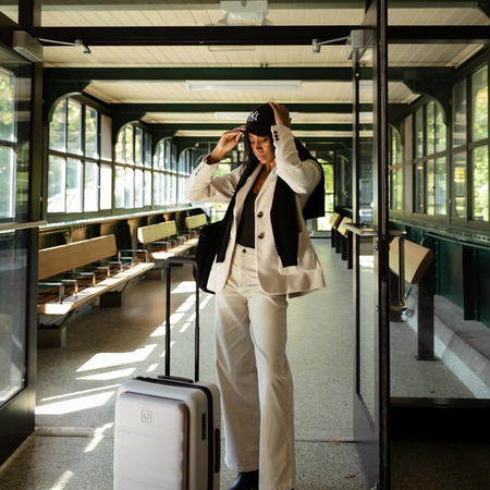 @chrissyford wearing blazer and jeans with a suitcase