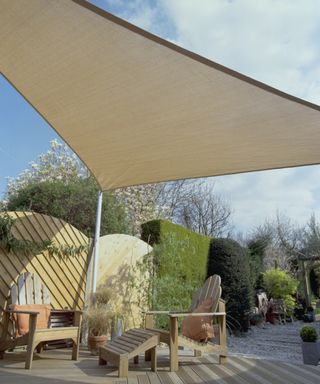 Cream shade sail over decking with wooden sun loungers
