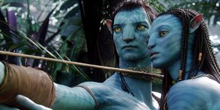 Avatar Jake draws his bow as Neytiri watches