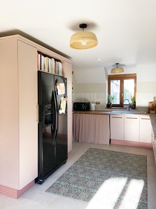 A pink kitchen with a black fridge with a built in surround
