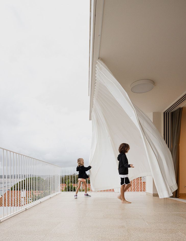 kids playing in terrace at Casa M against blue skies and wind blowing off curtain