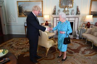 Boris Johnson wears a suit and shakes hands with Queen Elizabeth II, who is wearing a turquoise dress