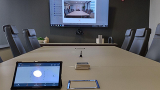A meeting room with a display for a videoconference powered by ClearOne audio solutions. 