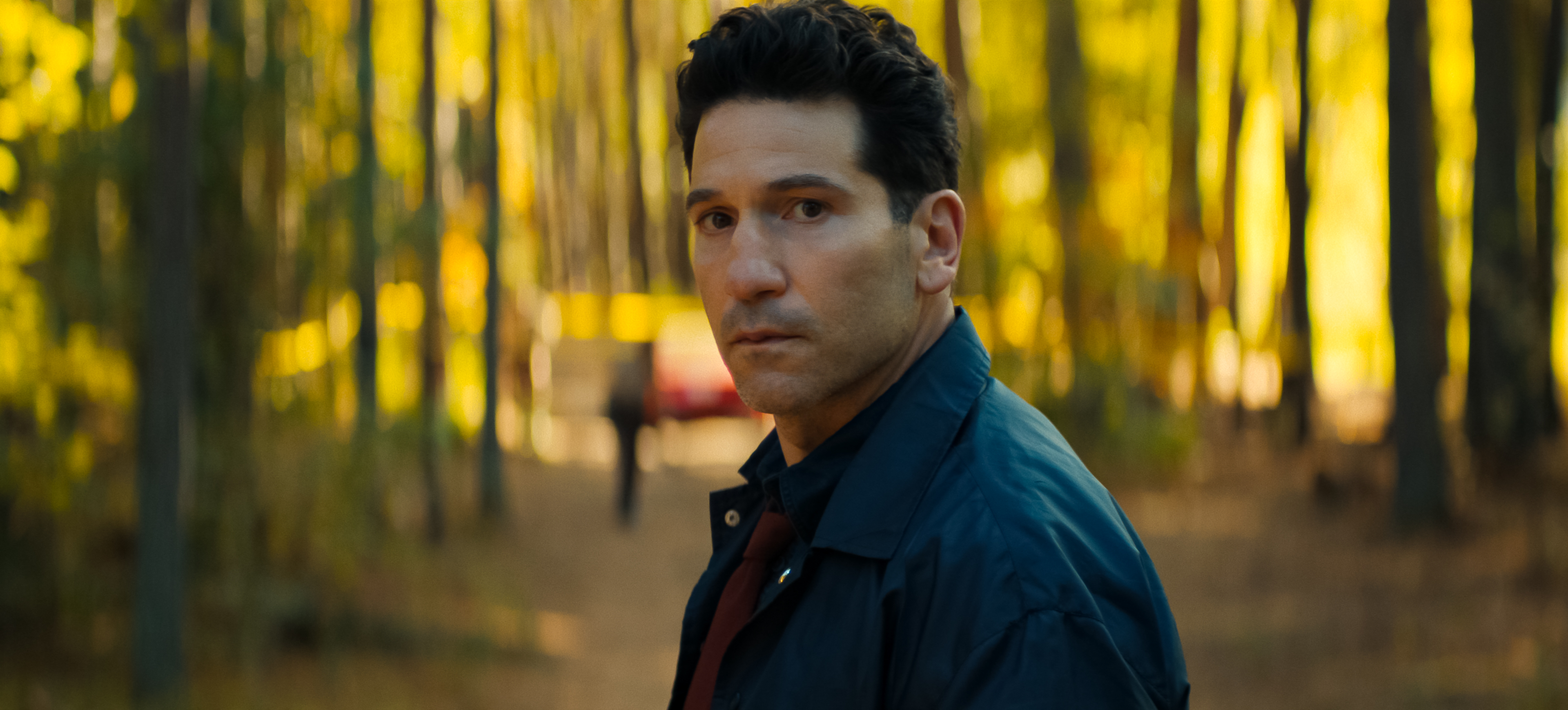 Jon Bernthal as Detective Jack Harperlooking surprised while standing in the middle of the road in the woods in a still from his and hers