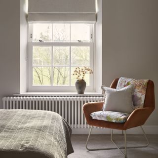 bedroom with orange armchair in front of window