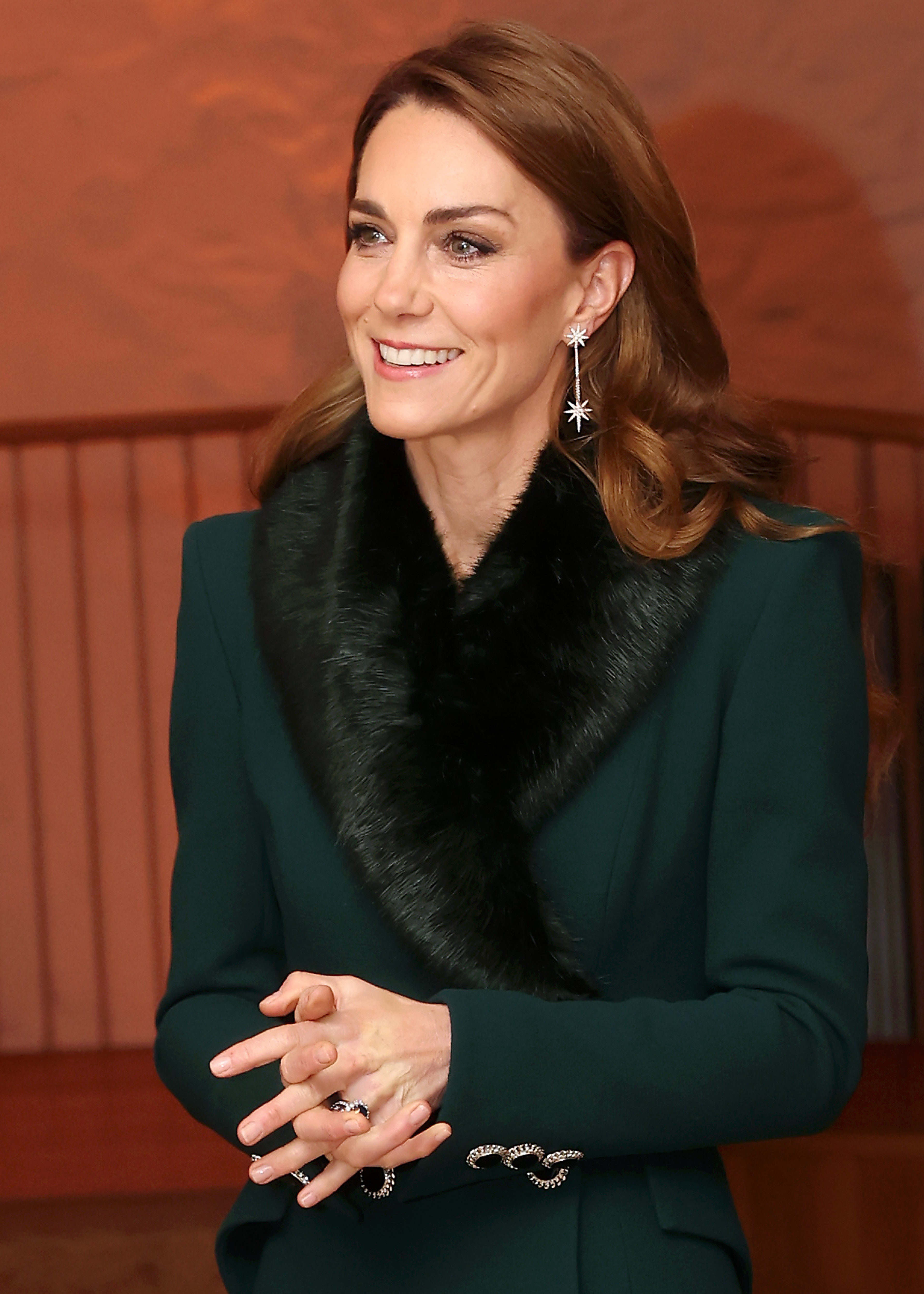 Kate Middleton wearing a green coat and fur scarf smiling